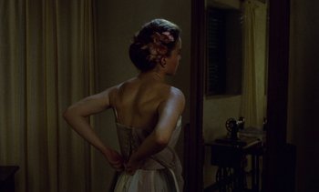 Movie still from “Chocolat” (1988), directed by Claire Denis – A woman in a white dress standing in front of a mirror; Medium shot, Over the shoulder angle