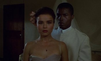 Movie still from “Chocolat” (1988), directed by Claire Denis – A man and a woman standing next to each other; Close Up shot, Low angle