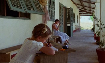 Movie still from “Chocolat” (1988), directed by Claire Denis – A woman sitting on a chair next to a little girl; Wide shot, Over the shoulder angle