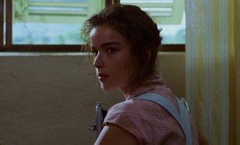 Movie still from “Chocolat” (1988), directed by Claire Denis – A young woman in a pink shirt is standing in front of a window; Close Up shot, Low angle