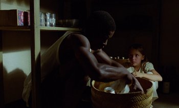 Movie still from “Chocolat” (1988), directed by Claire Denis – A man and a little girl in a basket; Medium shot, Low angle
