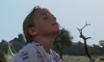 Movie still from “Chocolat” (1988), directed by Claire Denis – A young girl with her eyes closed in a field; Close Up shot, Low angle