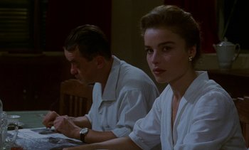 Movie still from “Chocolat” (1988), directed by Claire Denis – A man and a woman sitting at a dinner table; Medium shot, Over the shoulder angle