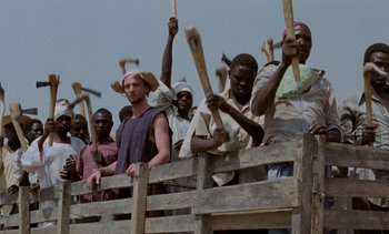 Movie still from “Chocolat” (1988), directed by Claire Denis – A group of men standing next to each other holding baseball bats; Medium shot, High angle