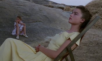 Movie still from “Chocolat” (1988), directed by Claire Denis – A young woman sitting in a chair next to a young girl; Medium shot, High angle