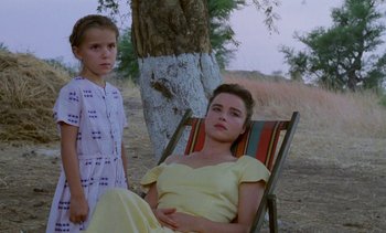 Movie still from “Chocolat” (1988), directed by Claire Denis – A woman sitting in a lawn chair next to a little girl; Medium shot, High angle