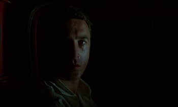 Movie still from “Chocolat” (1988), directed by Claire Denis – A man sitting in a chair in the dark; Close Up shot, Low angle
