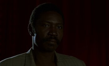 Movie still from “Chocolat” (1988), directed by Claire Denis – A man with a beard is looking at the camera; Close Up shot, Low angle