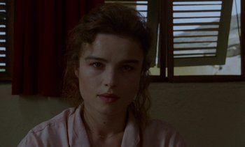 Movie still from “Chocolat” (1988), directed by Claire Denis – A young woman is sitting in front of a window; Close Up shot, Over the shoulder angle