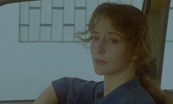 Movie still from “Chocolat” (1988), directed by Claire Denis – A young woman is sitting in front of a wall; Close Up shot, Low angle