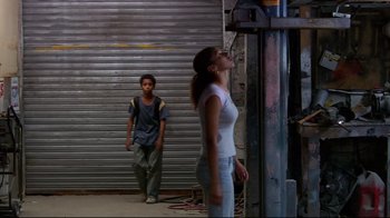 Movie still from “Chop Shop” (2007), directed by Ramin Bahrani – A woman standing next to a man in a doorway; Wide shot, Low angle