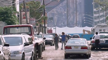 Movie still from “Chop Shop” (2007), directed by Ramin Bahrani – A couple of people walking down a street next to a bunch of parked cars; Extreme Wide shot, Low angle