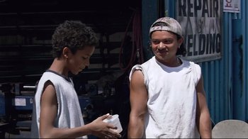 Movie still from “Chop Shop” (2007), directed by Ramin Bahrani – Two young men standing next to each other in front of a garage; Medium shot, Low angle