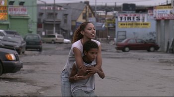 Movie still from “Chop Shop” (2007), directed by Ramin Bahrani – A young woman holding a young boy on her back; Medium shot, Low angle