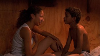 Movie still from “Chop Shop” (2007), directed by Ramin Bahrani – A woman and a young boy sitting on the ground; Medium shot, High angle