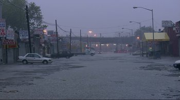 Movie still from “Chop Shop” (2007), directed by Ramin Bahrani – Cars are driving down a flooded street in the rain; Extreme Wide shot, High angle