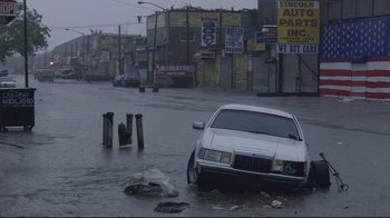 Movie still from “Chop Shop” (2007), directed by Ramin Bahrani – A car is parked in the middle of a flooded street; Extreme Wide shot, High angle