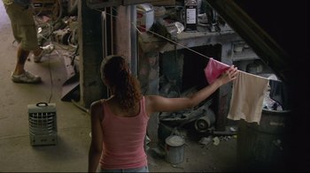 Movie still from “Chop Shop” (2007), directed by Ramin Bahrani – A woman in a pink tank top hanging a pink kite; Medium shot, High angle