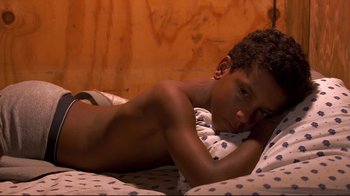 Movie still from “Chop Shop” (2007), directed by Ramin Bahrani – A young boy laying on a bed with his head on a pillow; Close Up shot, High angle