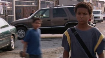 Movie still from “Chop Shop” (2007), directed by Ramin Bahrani – Two young people walking down the street in front of a car; Medium shot, Low angle