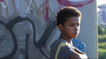 Movie still from “Chop Shop” (2007), directed by Ramin Bahrani – A young boy holding a tool in front of a graffiti wall; Close Up shot, Low angle