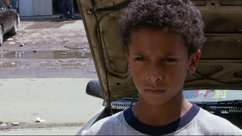 Movie still from “Chop Shop” (2007), directed by Ramin Bahrani – A young boy standing in front of an open car hood; Close Up shot, High angle