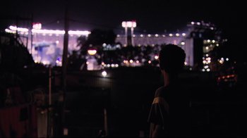 Movie still from “Chop Shop” (2007), directed by Ramin Bahrani – A man standing in front of a city at night; Medium shot, Over the shoulder angle