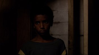 Movie still from “Chop Shop” (2007), directed by Ramin Bahrani – A young boy standing in a dark room; Close Up shot, High angle