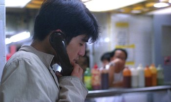 Movie still from “Chungking Express” (1994), directed by Kar-Wai Wong – A man talking on a phone while sitting in a booth; Close Up shot, Over the shoulder angle