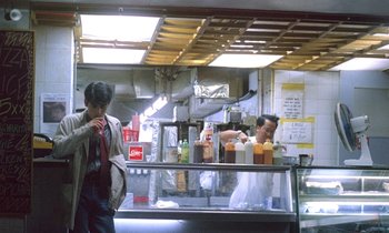 Movie still from “Chungking Express” (1994), directed by Kar-Wai Wong – A man standing in front of a counter in a restaurant; Wide shot, High angle