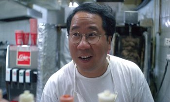 Movie still from “Chungking Express” (1994), directed by Kar-Wai Wong – A man in a white shirt is holding a donut; Close Up shot, Low angle