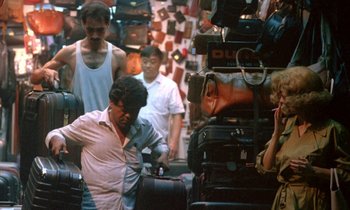 Movie still from “Chungking Express” (1994), directed by Kar-Wai Wong – A group of people standing next to a pile of suitcases; Medium shot, High angle