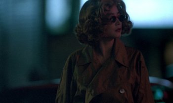 Movie still from “Chungking Express” (1994), directed by Kar-Wai Wong – A woman with curly red hair wearing sunglasses and a brown jacket; Close Up shot, Over the shoulder angle