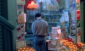 Movie still from “Chungking Express” (1994), directed by Kar-Wai Wong – A man standing in front of an open case of oranges; Wide shot, High angle