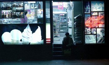Movie still from “Chungking Express” (1994), directed by Kar-Wai Wong – A man sitting on steps in front of a store window; Wide shot, High angle