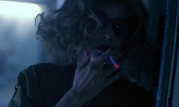 Movie still from “Chungking Express” (1994), directed by Kar-Wai Wong – A woman smoking a cigarette in a dark room; Close Up shot, Over the shoulder angle