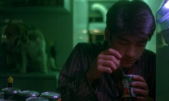 Movie still from “Chungking Express” (1994), directed by Kar-Wai Wong – A man sitting at a table with a cup in his hand; Medium shot, Over the shoulder angle