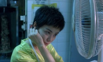 Movie still from “Chungking Express” (1994), directed by Kar-Wai Wong – A woman sitting in front of a fan in a room; Close Up shot, High angle