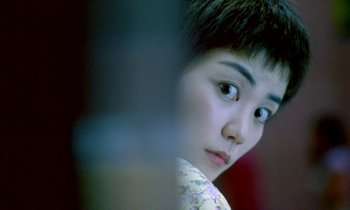 Movie still from “Chungking Express” (1994), directed by Kar-Wai Wong – A young woman with short brown hair looking at the camera; Close Up shot, Over the shoulder angle