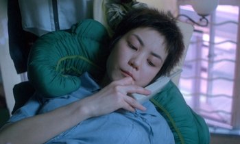 Movie still from “Chungking Express” (1994), directed by Kar-Wai Wong – A woman laying in a bed with a cell phone in her hand; Close Up shot, High angle