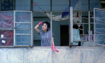 Movie still from “Chungking Express” (1994), directed by Kar-Wai Wong – A woman in a plaid shirt and pink gloves looking out of a window; Medium shot, Low angle