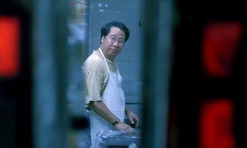 Movie still from “Chungking Express” (1994), directed by Kar-Wai Wong – A man wearing an apron standing in front of an oven; Medium shot, Low angle