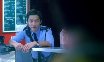 Movie still from “Chungking Express” (1994), directed by Kar-Wai Wong – A man sitting at a table in front of a bottle; Medium shot, Over the shoulder angle