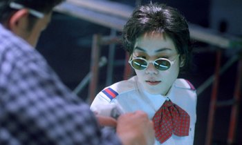 Movie still from “Chungking Express” (1994), directed by Kar-Wai Wong – A woman wearing sunglasses and a red bow tie; Close Up shot, Over the shoulder angle