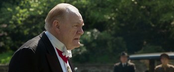 Movie still from “Churchill” (2017), directed by Jonathan Teplitzky – An older man in a suit and bow tie; Close Up shot, Over the shoulder angle