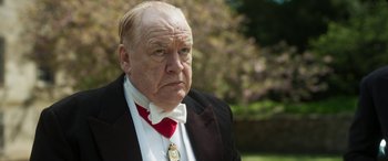 Movie still from “Churchill” (2017), directed by Jonathan Teplitzky – An older man wearing a suit and red tie; Close Up shot, Low angle