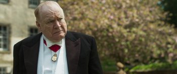 Movie still from “Churchill” (2017), directed by Jonathan Teplitzky – An older man wearing a suit and a red neck tie; Close Up shot, Over the shoulder angle