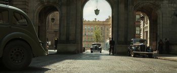 Movie still from “Churchill” (2017), directed by Jonathan Teplitzky – An old car is parked under an archway; Extreme Wide shot, Low angle