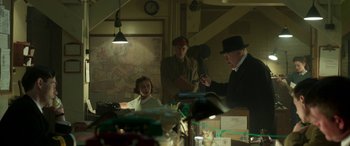 Movie still from “Churchill” (2017), directed by Jonathan Teplitzky – A group of people standing in a room; Medium shot, Over the shoulder angle