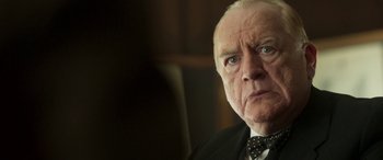 Movie still from “Churchill” (2017), directed by Jonathan Teplitzky – An older man wearing a suit and a bow tie; Close Up shot, Over the shoulder angle